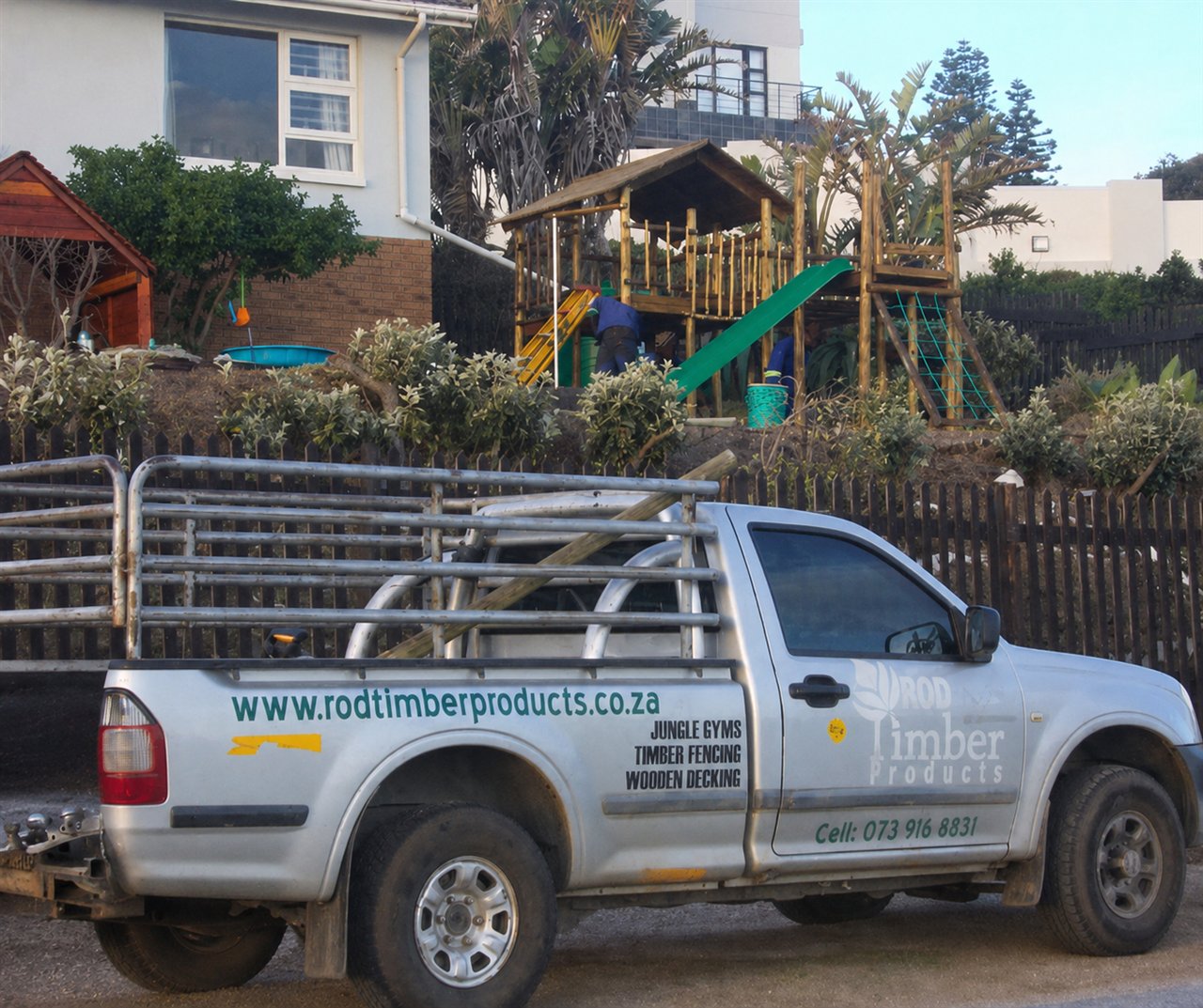A custom timber jungle gym built by Rod Timber Products at a coastal home, with the branded company bakkie in front