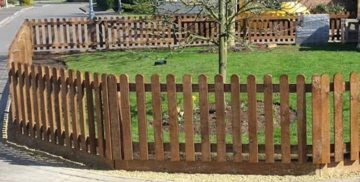 Stained timber picket fence around a garden