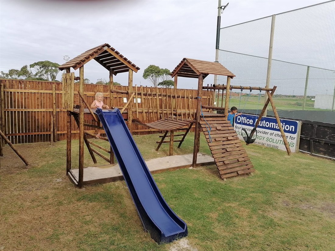 Timber jungle gym with blue slide and climbing wall